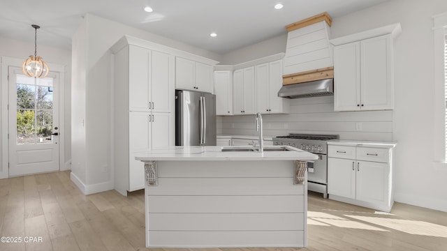 kitchen with decorative light fixtures, stainless steel appliances, an island with sink, decorative backsplash, and ventilation hood