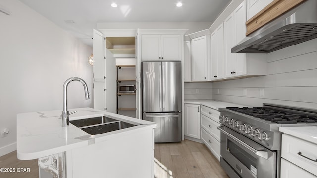 kitchen featuring extractor fan, a center island with sink, appliances with stainless steel finishes, backsplash, and light stone countertops