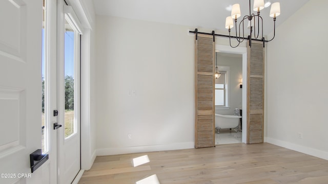 entryway with light hardwood / wood-style floors, a chandelier, and a healthy amount of sunlight