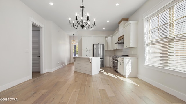 kitchen with decorative light fixtures, a center island with sink, a wealth of natural light, stainless steel appliances, and white cabinets