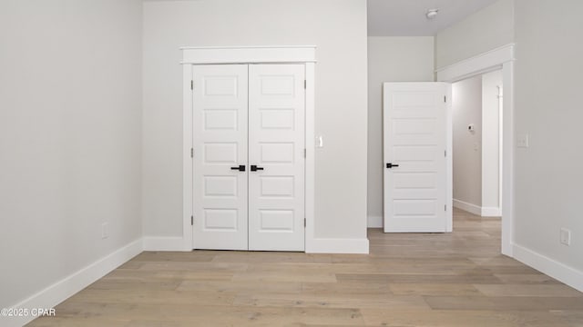 unfurnished bedroom with a closet and light wood-type flooring