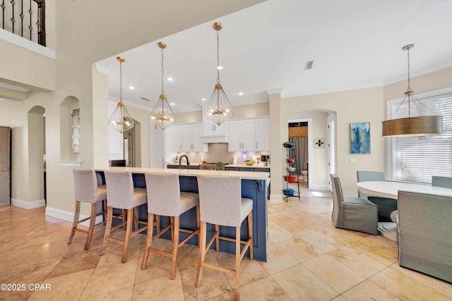 kitchen featuring a breakfast bar, arched walkways, light countertops, and decorative backsplash