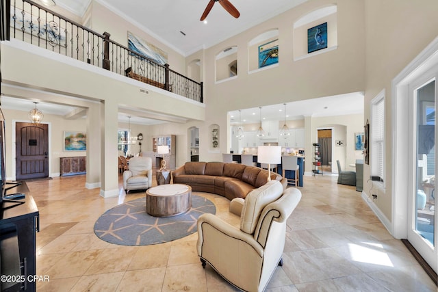 living area featuring light tile patterned floors, baseboards, arched walkways, a ceiling fan, and crown molding