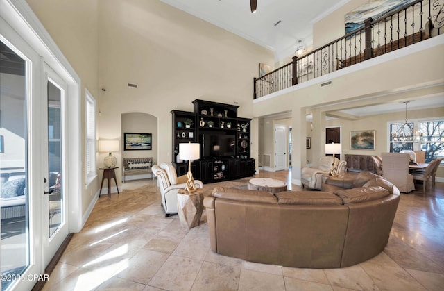 living room with visible vents, baseboards, a towering ceiling, crown molding, and a notable chandelier