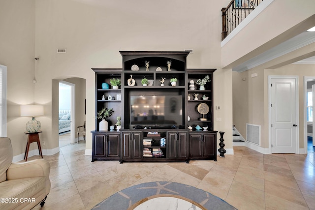 living room featuring a towering ceiling, stairway, visible vents, and arched walkways