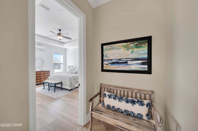 hall with a raised ceiling, visible vents, a wall mounted AC, and wood finished floors