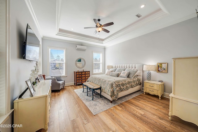 bedroom featuring visible vents, a raised ceiling, crown molding, light wood-style floors, and a wall mounted AC