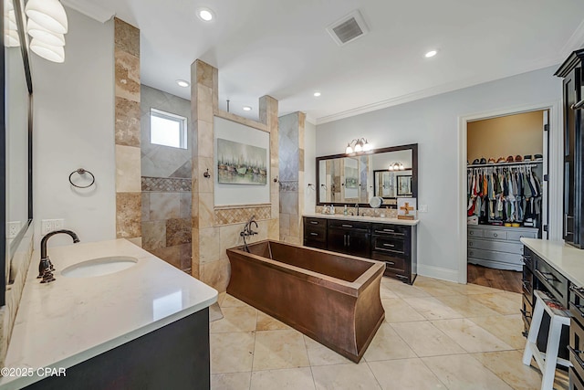 bathroom with visible vents, a sink, a freestanding tub, a walk in shower, and two vanities