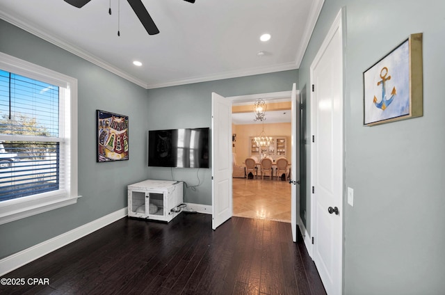 living area with baseboards, ornamental molding, dark wood-type flooring, and ceiling fan with notable chandelier