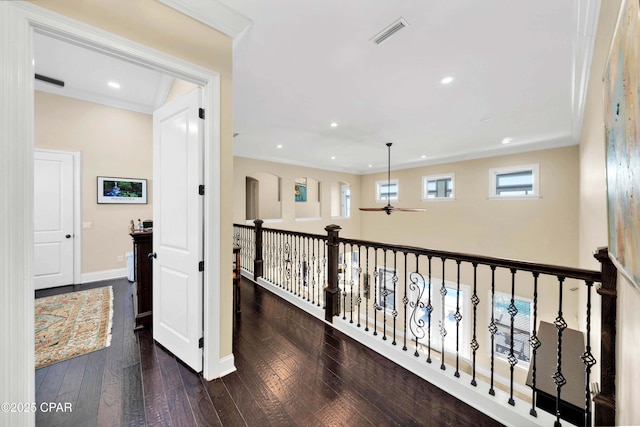 corridor featuring visible vents, baseboards, hardwood / wood-style flooring, and crown molding