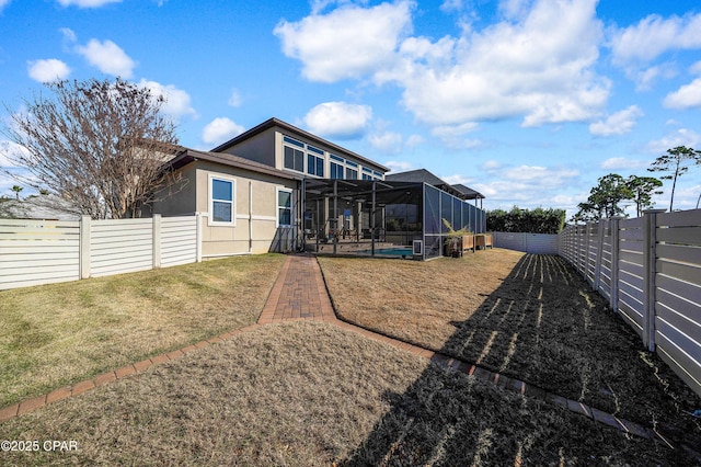 rear view of property featuring glass enclosure, a patio, a fenced backyard, a lawn, and stucco siding