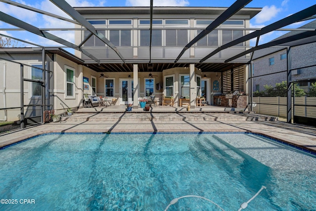 outdoor pool with a ceiling fan, glass enclosure, and a patio