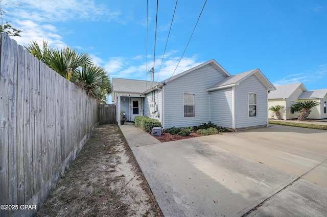 view of property exterior with concrete driveway and fence