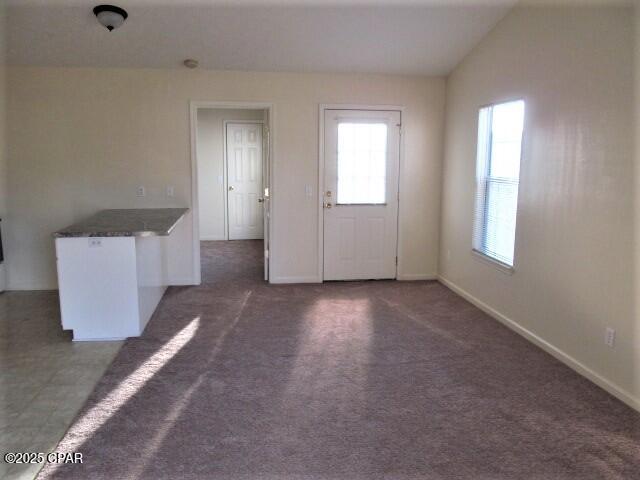 interior space featuring vaulted ceiling and dark carpet