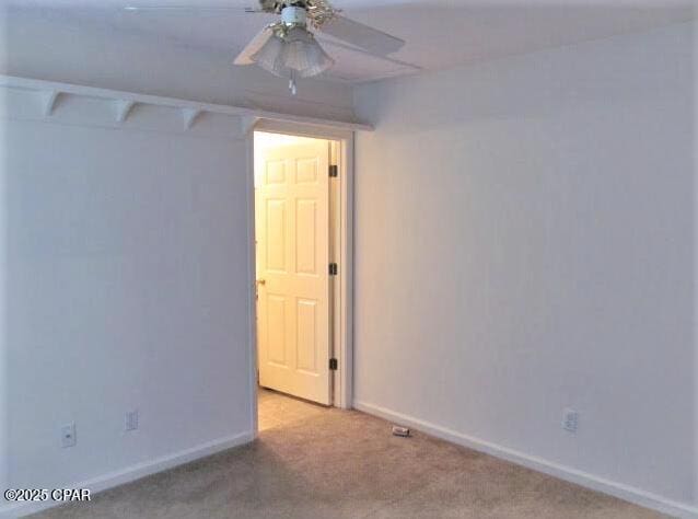 empty room featuring ceiling fan and light carpet