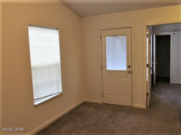 interior space featuring lofted ceiling, baseboards, and dark colored carpet