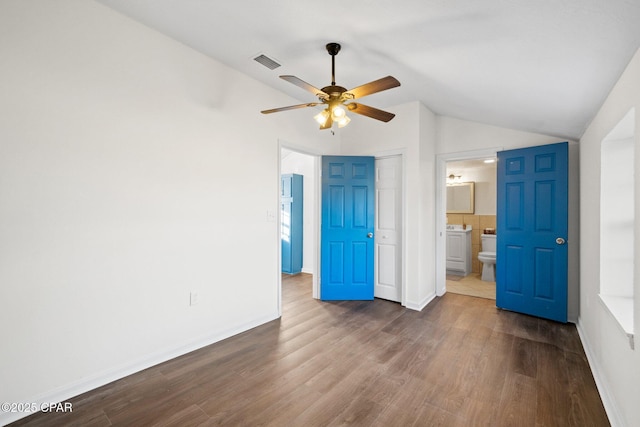 unfurnished bedroom with vaulted ceiling, ceiling fan, connected bathroom, and hardwood / wood-style floors