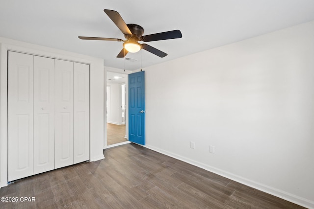 unfurnished bedroom with ceiling fan, a closet, and dark hardwood / wood-style floors