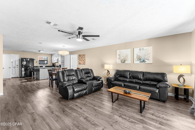 living room with a textured ceiling, ceiling fan, and hardwood / wood-style floors