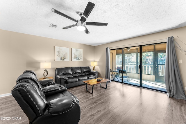 living room featuring ceiling fan, a textured ceiling, and hardwood / wood-style flooring