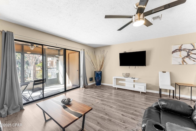 living room featuring ceiling fan, a textured ceiling, and hardwood / wood-style floors