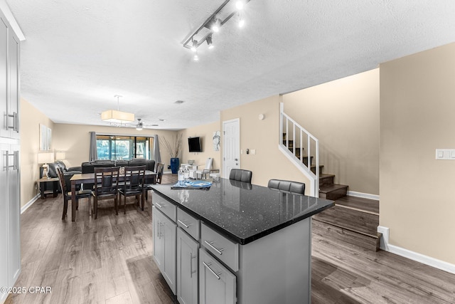 kitchen with ceiling fan, hardwood / wood-style flooring, a center island, and gray cabinetry