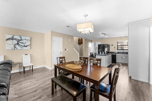 dining room with sink, a textured ceiling, and light hardwood / wood-style flooring