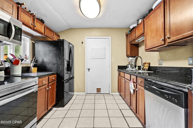 kitchen with sink, dark stone countertops, stainless steel appliances, and light tile patterned floors