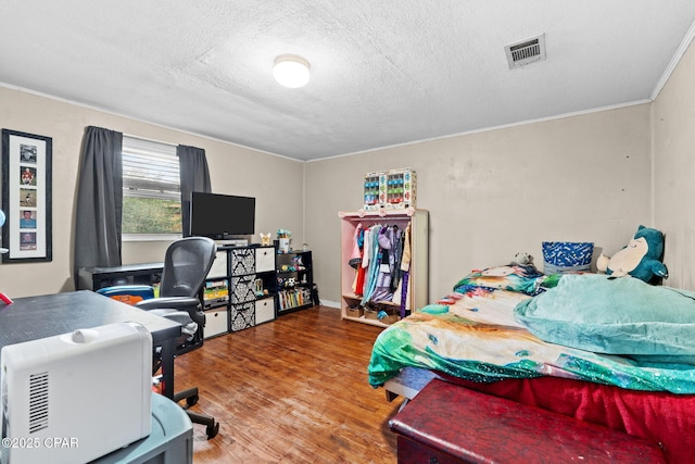 bedroom with crown molding, wood-type flooring, and a textured ceiling