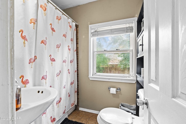 bathroom with a shower with shower curtain, toilet, and tile patterned floors