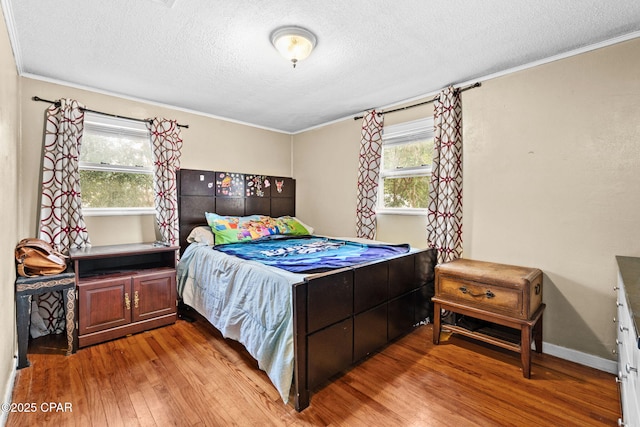 bedroom featuring light hardwood / wood-style floors, crown molding, and a textured ceiling