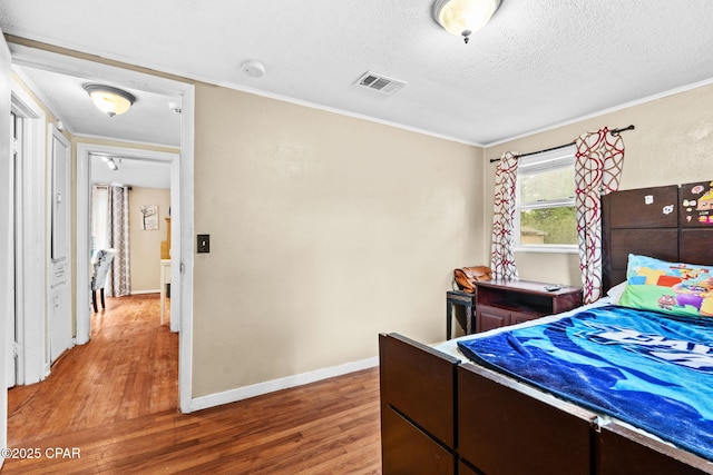 bedroom with hardwood / wood-style flooring, crown molding, and a textured ceiling