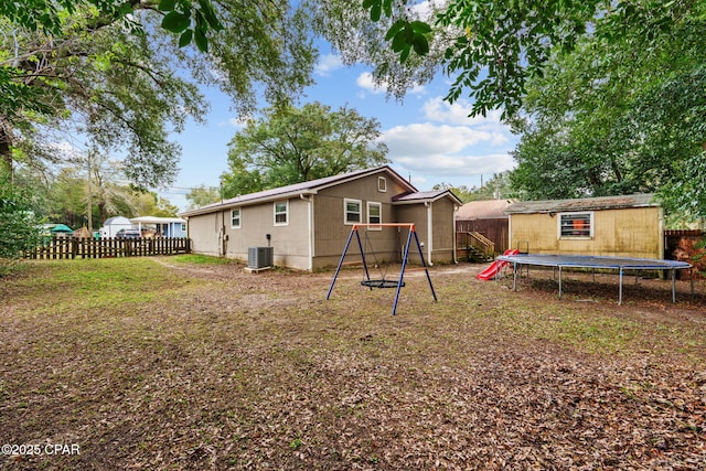 back of property featuring a shed, a trampoline, and central AC unit