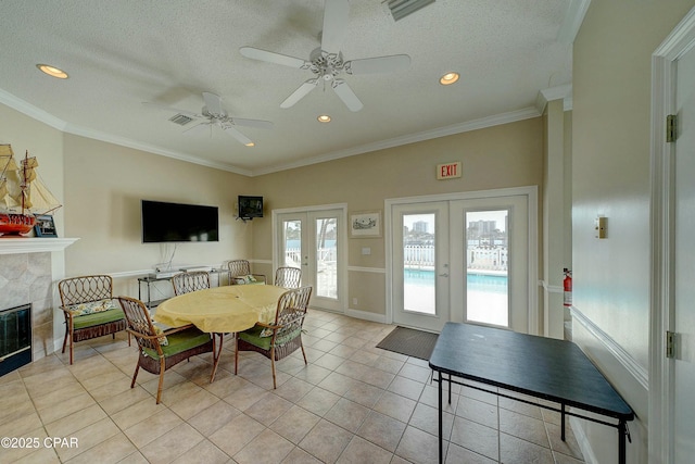 dining space featuring a fireplace, ornamental molding, a textured ceiling, and french doors