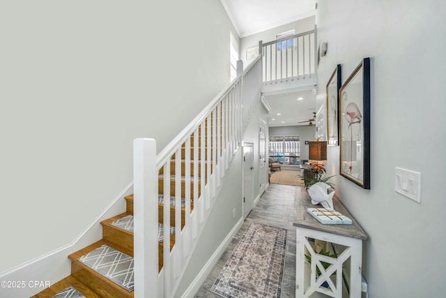 stairs featuring hardwood / wood-style flooring, crown molding, and a towering ceiling