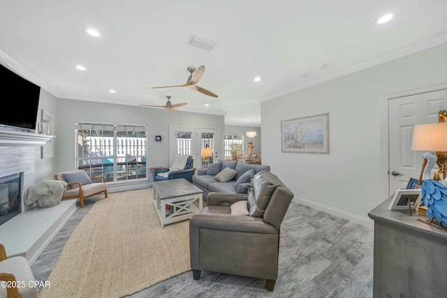 living room featuring ceiling fan, crown molding, and a fireplace