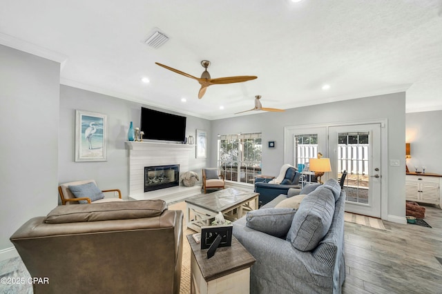 living room featuring ceiling fan, ornamental molding, and wood-type flooring