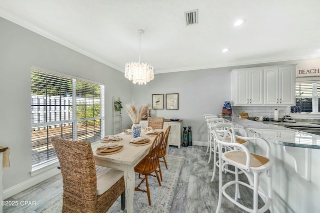 dining space featuring crown molding, a chandelier, and light wood-type flooring