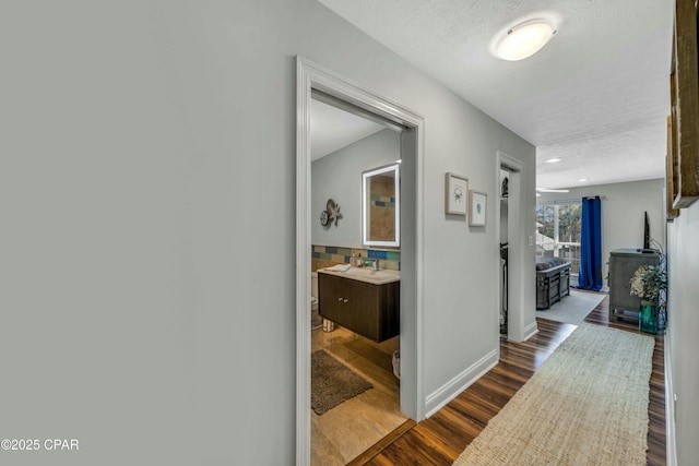 hallway with a textured ceiling and wood-type flooring