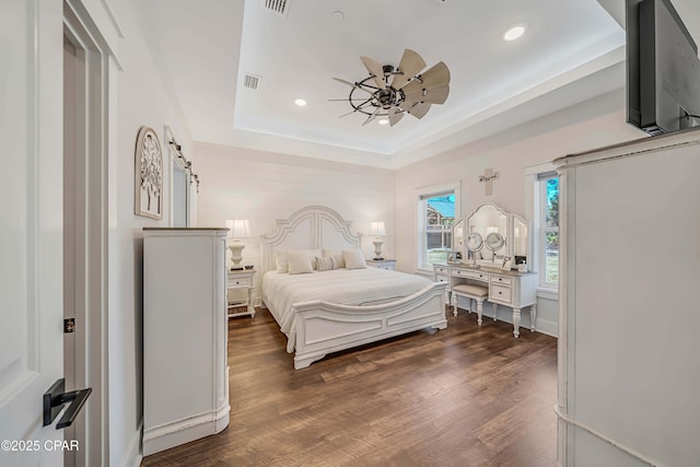 bedroom with a tray ceiling, dark wood-type flooring, and ceiling fan