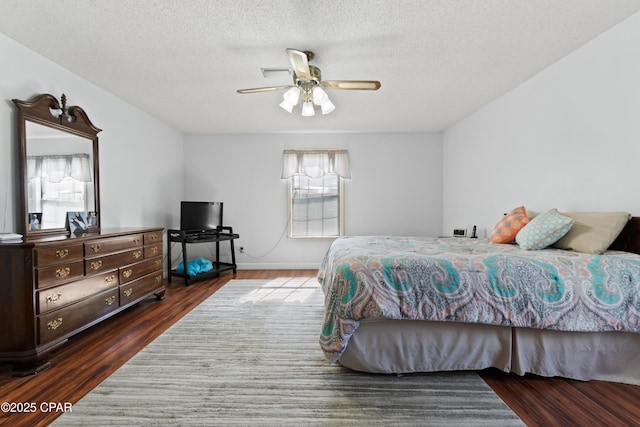 bedroom featuring ceiling fan, dark wood-type flooring, and a textured ceiling