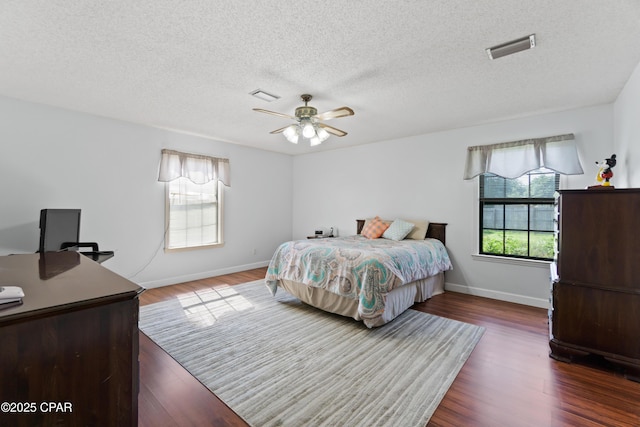 bedroom featuring ceiling fan, dark wood-type flooring, and a textured ceiling