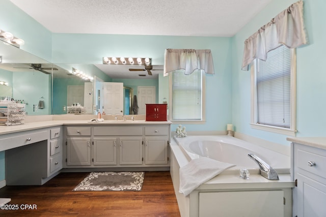 bathroom with vanity, ceiling fan, a bath, and a textured ceiling