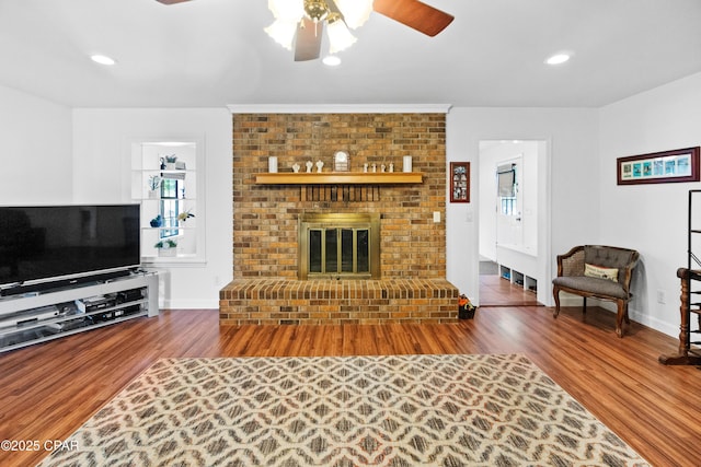 living room with a fireplace, hardwood / wood-style floors, ceiling fan, and crown molding