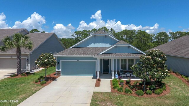 view of front of property with a porch, a garage, and a front lawn