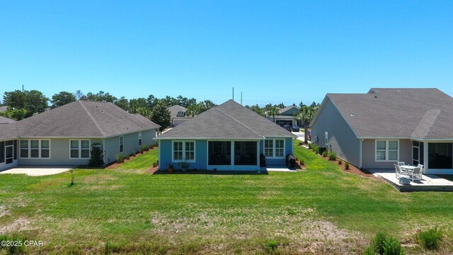 rear view of house featuring a yard, a patio area, and a sunroom