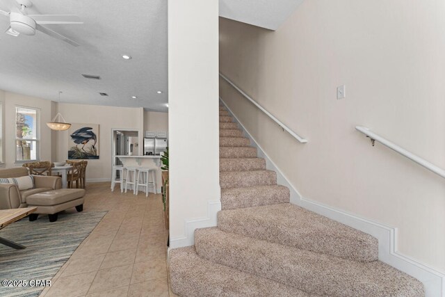 stairway featuring tile patterned floors and ceiling fan