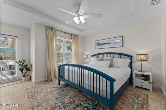 bedroom featuring ceiling fan, a raised ceiling, and carpet