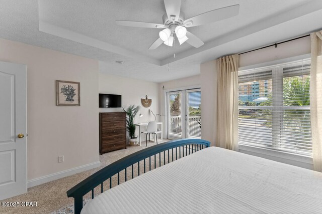 bedroom with a raised ceiling, access to outside, light colored carpet, and a textured ceiling