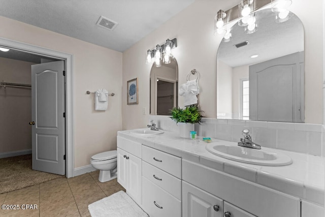 bathroom with tile patterned flooring, vanity, a textured ceiling, and toilet